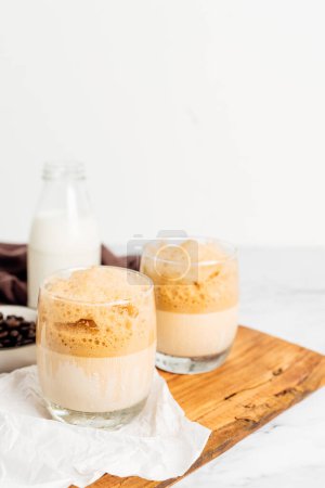 Photo for Iced or frappe coffee smoothie on a glass cup and Roasted coffee beans, and milk on marble backdrop. Copy space for your text. vertical photo - Royalty Free Image