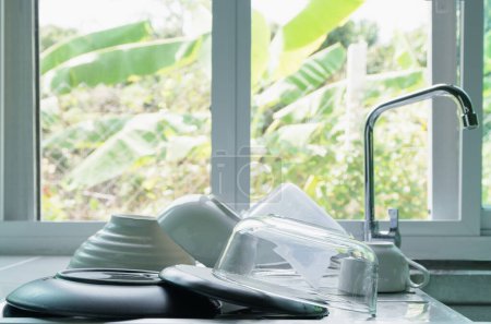 Téléchargez les photos : Assiettes propres, bols et tasses à café sont placés sur l'évier dans la cuisine à la maison. - en image libre de droit