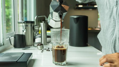 Foto de Personas que utilizan italiano clásico Moka café olla verter, cafetera con equipo herramienta de elaboración de barra de mármol en la cocina casera - Imagen libre de derechos