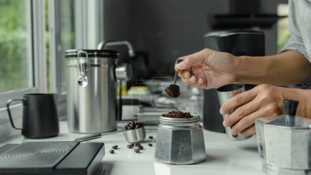 Photo for Powder coffee on a stainless spoon with hand people pour Roasted coffee for espresso coffee into the cup with equipment tool brewing Italian Moka pot, preparation coffee - Royalty Free Image
