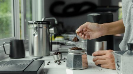 Photo for Powder coffee on a stainless spoon with hand people pour Roasted coffee for espresso coffee into the cup with equipment tool brewing Italian Moka pot, preparation coffee - Royalty Free Image