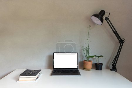 Téléchargez les photos : Bureau à domicile avec ordinateur portable et livre sur la décoration de bureau cadre blanc comme lampe et plantes de maison avec des décorations intérieures de style loft mural. gros plan - en image libre de droit
