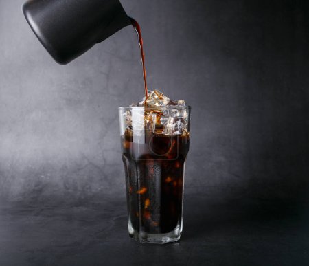 Foto de Café envasado de café americano en un vaso transparente con hielo. y granos de café tostados en una foto de estudio de fondo negro - Imagen libre de derechos
