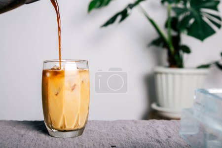 Photo for A pitcher Pour brewed coffee and brew cold black coffee on a mug with roasted Arabica beans on a white table and coffee maker. home made coffee - Royalty Free Image