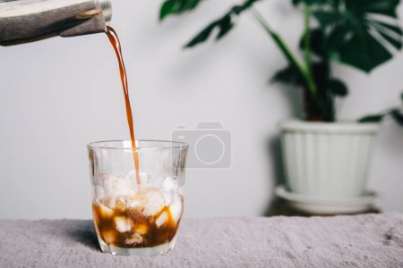 Photo for Poured coffee of ice americano coffee into a transparent glass on table , homemade coffee - Royalty Free Image