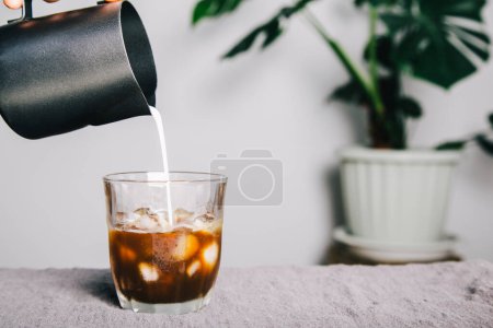 Photo for Hand of barista using a pitcher Pour milk making latte coffee on table and coffee maker. homemade coffee - Royalty Free Image