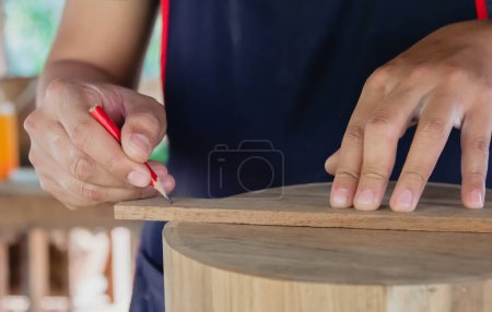 Photo for Craftsman using the pencil marking make on the wooden product working at carpentry workshop  furniture project - Royalty Free Image