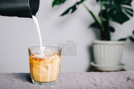 Téléchargez les photos : Pichet Verser le lait faisant café latte sur la table et la cafetière. café fait maison - en image libre de droit