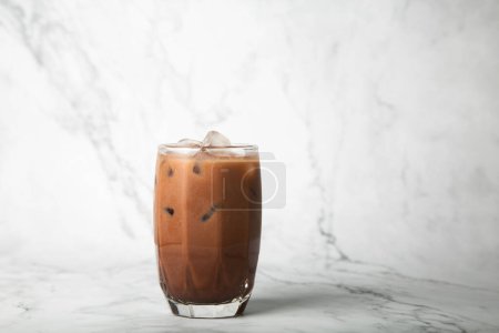 Téléchargez les photos : Cacao glacé sur le lait dans la tasse sur fond de marbre - en image libre de droit