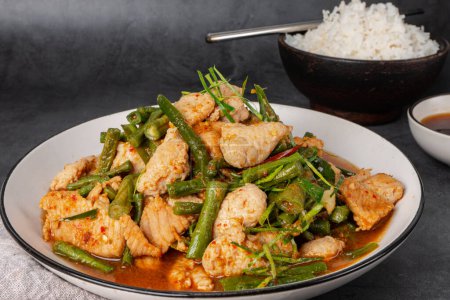  Tasty Stir-fried pork and red hot curry paste with asparagus bean or long bean and  Ingredients are oyster sauce, fish sauce, sugar, kaffir lime leaves in the dish Eat with cooked rice. Thai cuisine