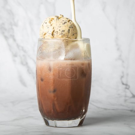 Photo for Pour the almond milk cream. Iced cocoa with vanilla ice cream in clear glass on marble Copy space for your text. square image - Royalty Free Image