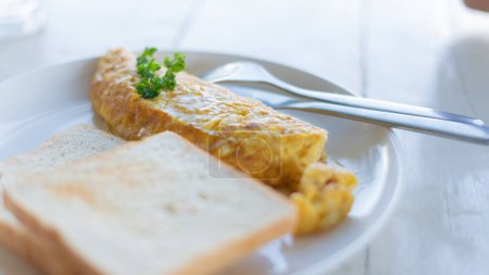 Photo for Delicious scrambled eggs on top with parsley and bread in a white plate on  wooden table - Royalty Free Image