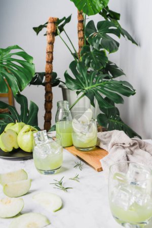 Photo for Refreshing delicious of iced guava juice in a glass and sliced guava placed on white marble, houseplant green plant background. Decorative Composition Drinks at Home . Vertical photo - Royalty Free Image