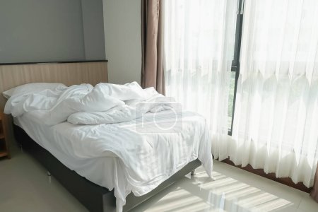 Foto de Un dormitorio blanco con cama blanca y sábanas, mantas y almohadas. está arruinando el despertar. dormir en el hotel por la mañana - Imagen libre de derechos