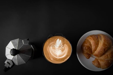 Foto de Café de arte latte en una taza blanca Dos lados con ollas Moka italianas, café y croissants, vista superior, fondo negro, espacio vacío, y tres intersecciones para su uso. - Imagen libre de derechos