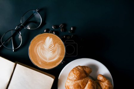 Téléchargez les photos : Café Latte art dans une tasse blanche, croissants, café torréfié aux haricots avec verres et agenda vue de dessus, fond noir, espace de copie votre texte - en image libre de droit