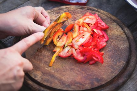 Téléchargez les photos : Gros plan, trancher ou trancher des tomates fraîches sur une planche à découper en bois, préparer l'assaisonnement et la cuisson. - en image libre de droit