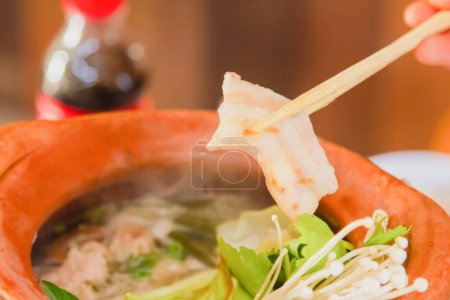 Chopsticks and tongs of hot pork belly put up to eat Shabu Hot Pot. Prepare eating food