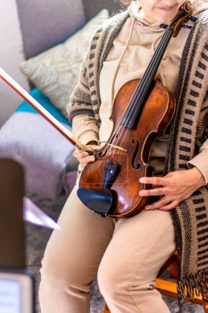 Téléchargez les photos : Violinist studying at home. Antique violin leaning on her. - en image libre de droit