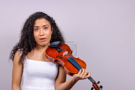 Téléchargez les photos : African girl violinist surprised with her mouth open. Surprise concept. - en image libre de droit