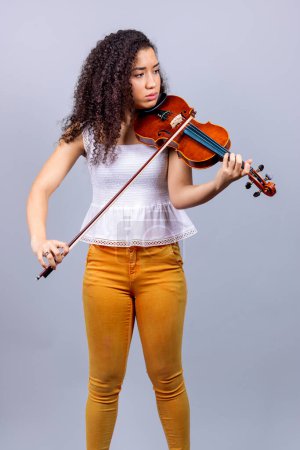 Téléchargez les photos : Beautiful young woman playing violin over gray - en image libre de droit