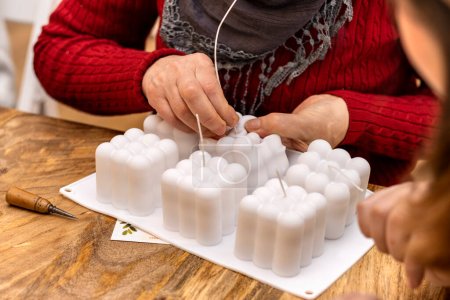 Foto de Elderly woman works silicone molds to make soy candles. Handmade soy wax candle workshop. - Imagen libre de derechos