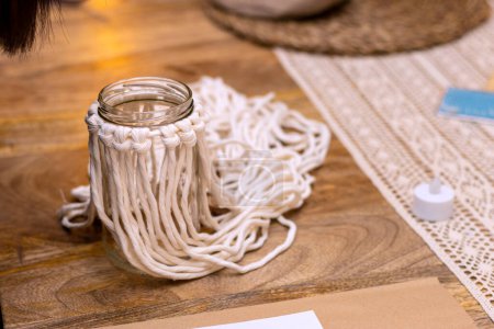Téléchargez les photos : Macrame. The art of knot tying. Middle-aged woman weaving on a glass jar with this technique. - en image libre de droit