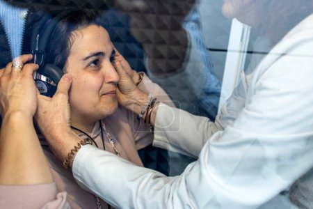 Photo for Audiology. Doctor places headphones in a soundproof room to a patient. - Royalty Free Image