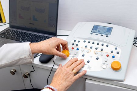 Photo for Audiology. Close-up of a doctor's hands handling the audio measuring equipment. - Royalty Free Image