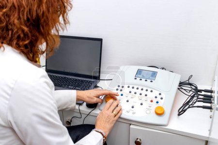 Photo for Joyous middle-aged doctor performing an audiometry test - Royalty Free Image