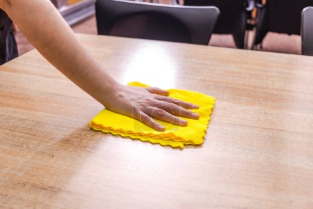 Foto de Camarera limpiando la mesa de bar con un paño amarillo - Imagen libre de derechos