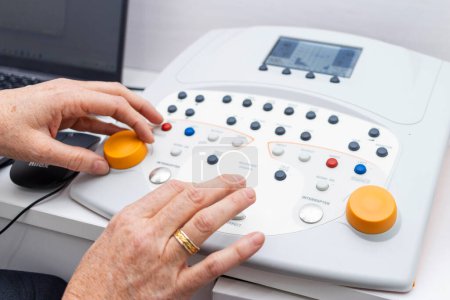 Photo for Close-up of a doctor's hands calibrating a hearing measurement machine - Royalty Free Image