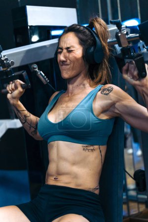 Foto de Fitness Inspiración: Mujer de mediana edad inspirando a otros con máquinas de gimnasia - Imagen libre de derechos