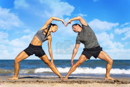 Photo for Smiling couple doing yoga exercises outdoors - Royalty Free Image
