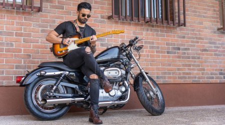 Téléchargez les photos : Guitariste hipster jouant une guitare électrique sur une moto - en image libre de droit