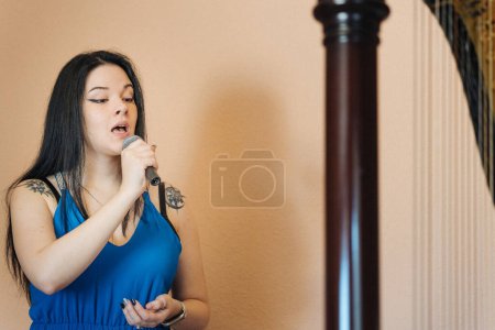 Photo for Latin girl singing along to a harp - Royalty Free Image