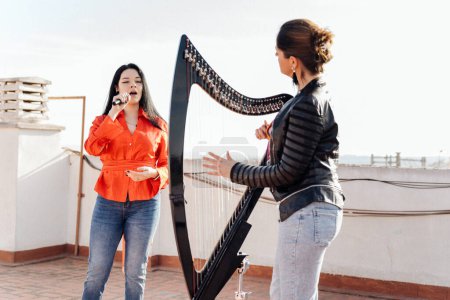Ungarische elektronische Harfe mit lateinischem Sänger beim Proben auf dem Dach des Gebäudes