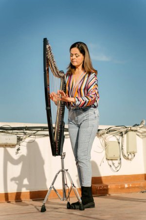 Photo for Professional harpist playing an electronic harp on the rooftop - Royalty Free Image