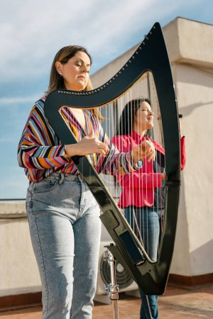 Photo for Harp and voice duo performing on the roof of the building - Royalty Free Image