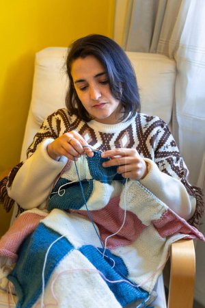 Middle aged woman knitting an elegant blanket for her home
