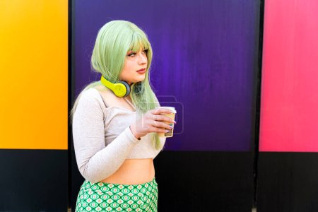 Modernes Mädchen mit grünen Haaren trinkt in Café an der Universität