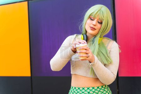 Modernes Mädchen mit grünen Haaren trinkt in Café an der Universität