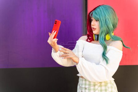 Modernes Mädchen mit roten und grünen Haaren macht ein Foto mit ihrem Handy