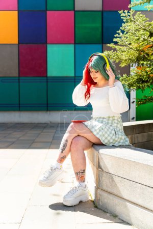 Modern girl with red and green hair with headphones waiting in the faculty