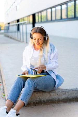 Estudiante universitario rumano de clase alta con auriculares sentados