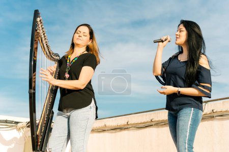 Photo for Harpist and vocalist doing a musical show on the roof - Royalty Free Image