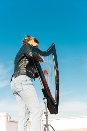 Photo for Modern harpist with an electronic harp playing outdoors - Royalty Free Image