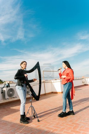 Photo for Modern harp and voice duo rehearsing on the roof of a building - Royalty Free Image