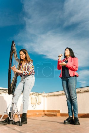 Photo for Modern harp and voice duo rehearsing on the roof of a building - Royalty Free Image
