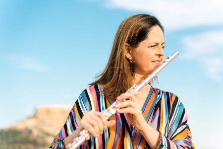 Portrait of a female flute player playing outdoors